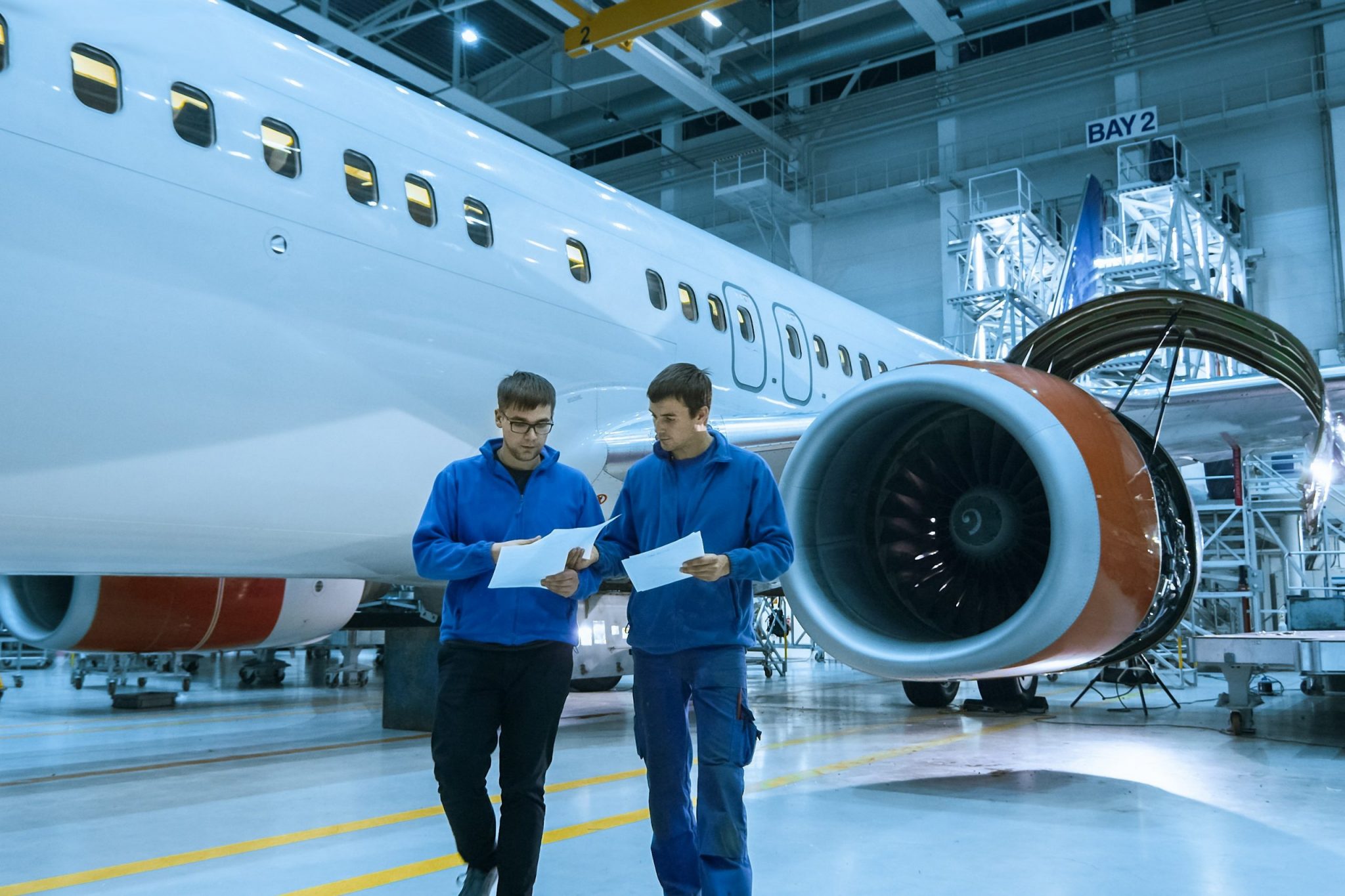 Aircraft maintenance mechanic uses tablet in front of a airplane cabin in a hangar.